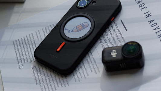 XTREM smart NFC phone case displaying a pencil icon, placed on a magazine with a camera nearby, showcasing customizable and creative lifestyle use